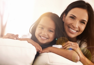 Mother and young daughter smiling on couch