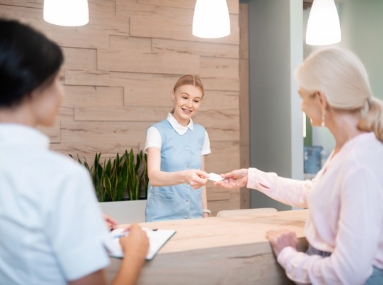 Dental receptionist handing a card to a patient