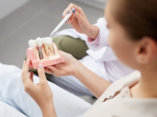 Dentist showing a dental implant model to a patient