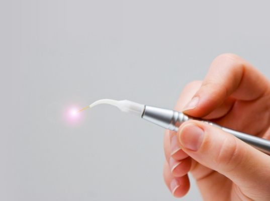 Hand holding a thin silver laser device