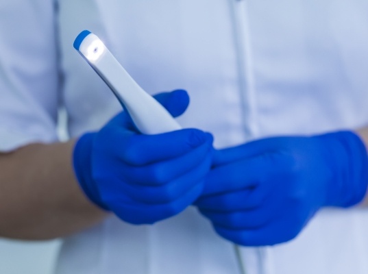 Dentist holding a thin white intraoral camera