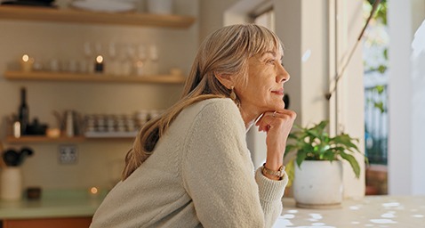 Senior woman smiling while looking out the window at home