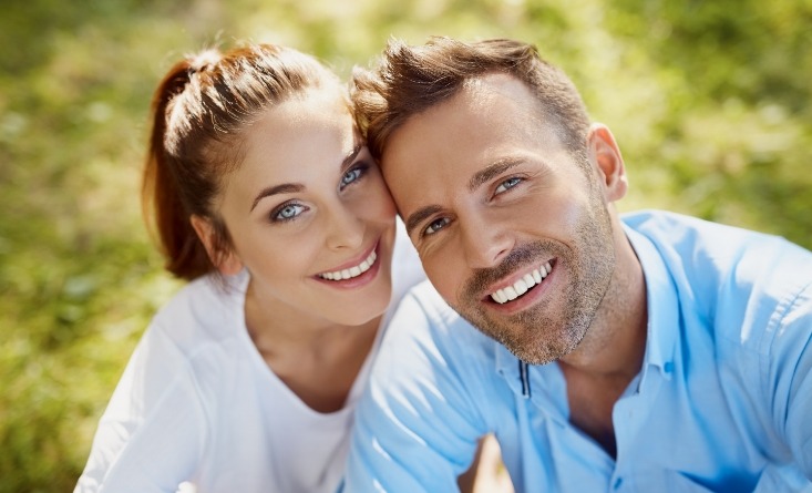 Smiling man and woman sitting in grass