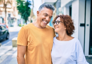 Man and woman smiling while walking down city sidewalk