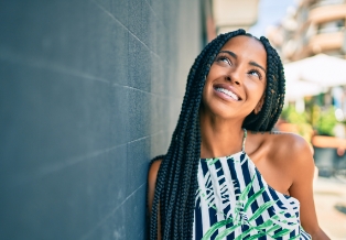 Smiling young woman leaning against brick wall