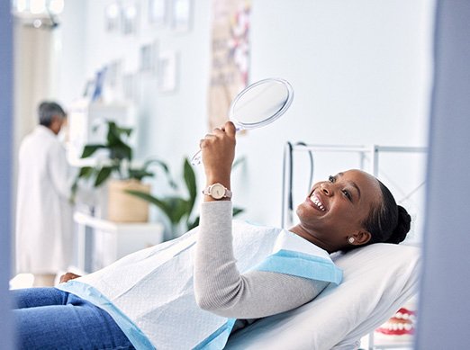 Woman smiling at reflection in handheld mirror