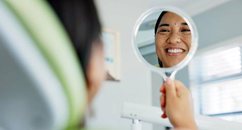 Woman smiling at reflection in dentist office