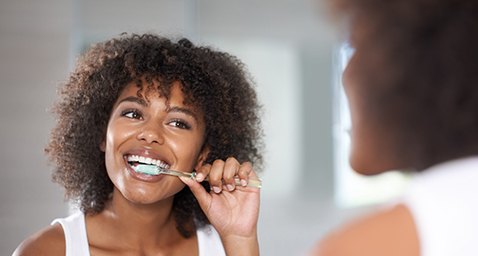 Woman smiling while brushing her teeth