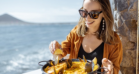 Smiling woman enjoying meal at restaurant on the water