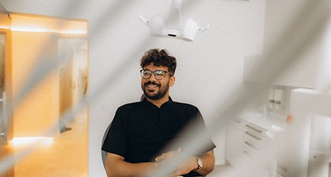 Patient with black glasses smiling in treatment chair