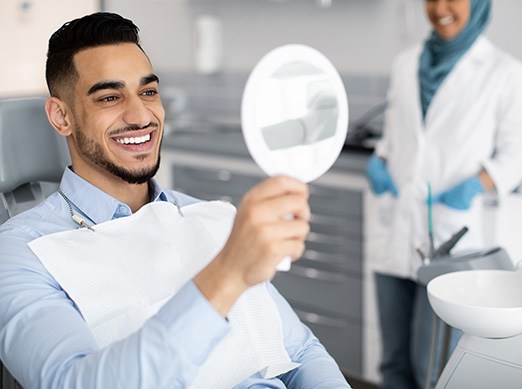 Man smiling at reflection in handheld mirror