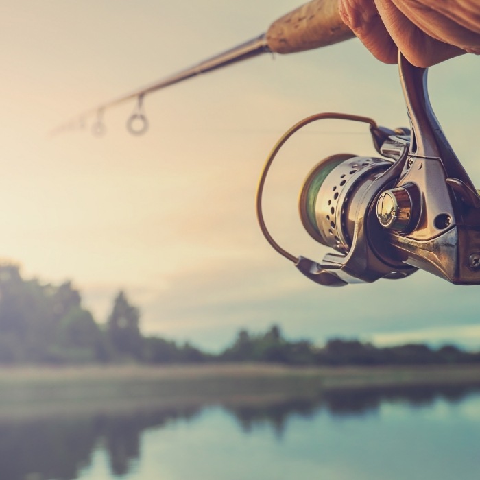 Close up of fishing rod with pond in background