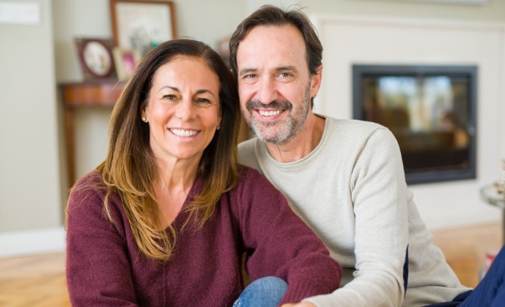 Man and woman smiling on couch after replacing missing teeth in Longmeadow