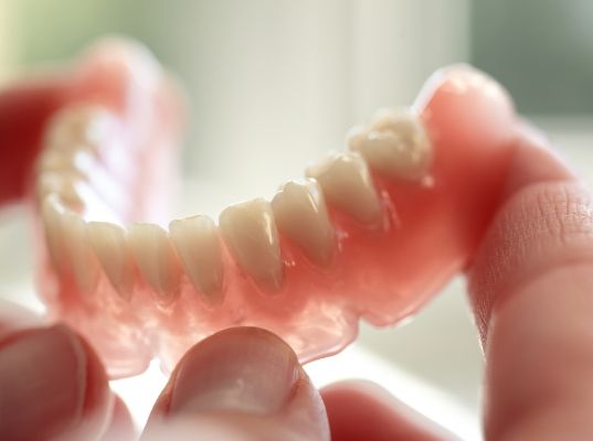 Hand holding a full denture