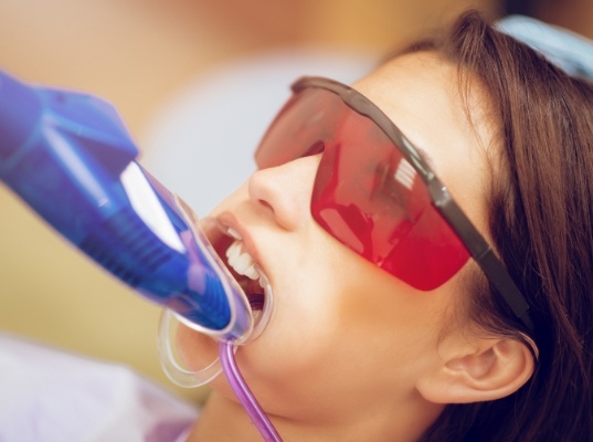 Girl in dental chair with fluoride trays over her teeth