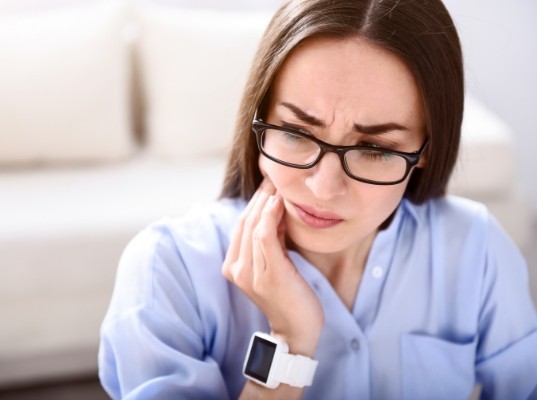 Woman holding the side of her jaw in pain