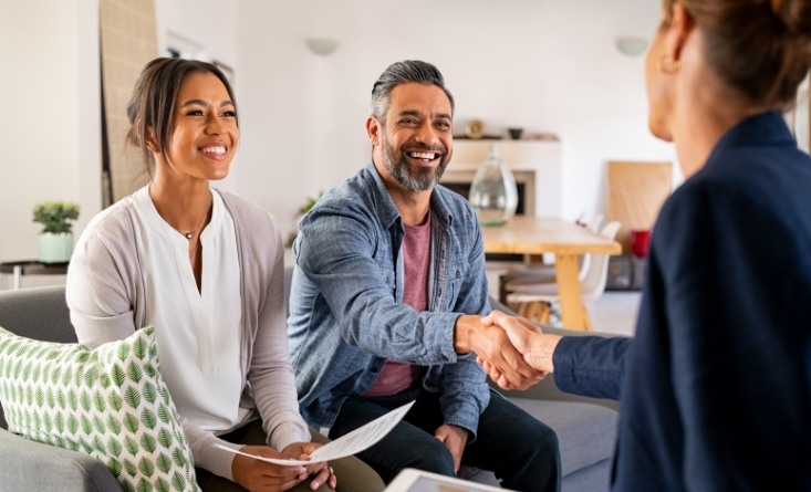 Smiling man shaking hands with person sitting across from him