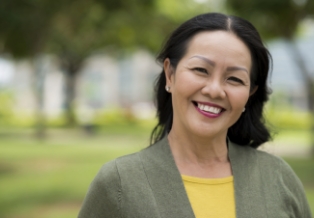 Woman in moss green jacket smiling outdoors