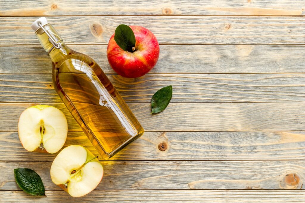 Apples and apple cider vinegar on table