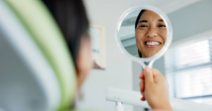 a patient holding a mirror and smiling
